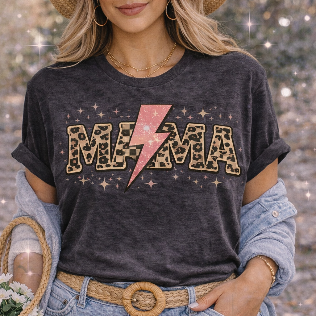 Woman wearing a dark charcoal vintage style t-shirt featuring the word MAMA in leopard print letters with a pink lightning bolt replacing the center letter, surrounded by sparkles for a trendy western glam look.